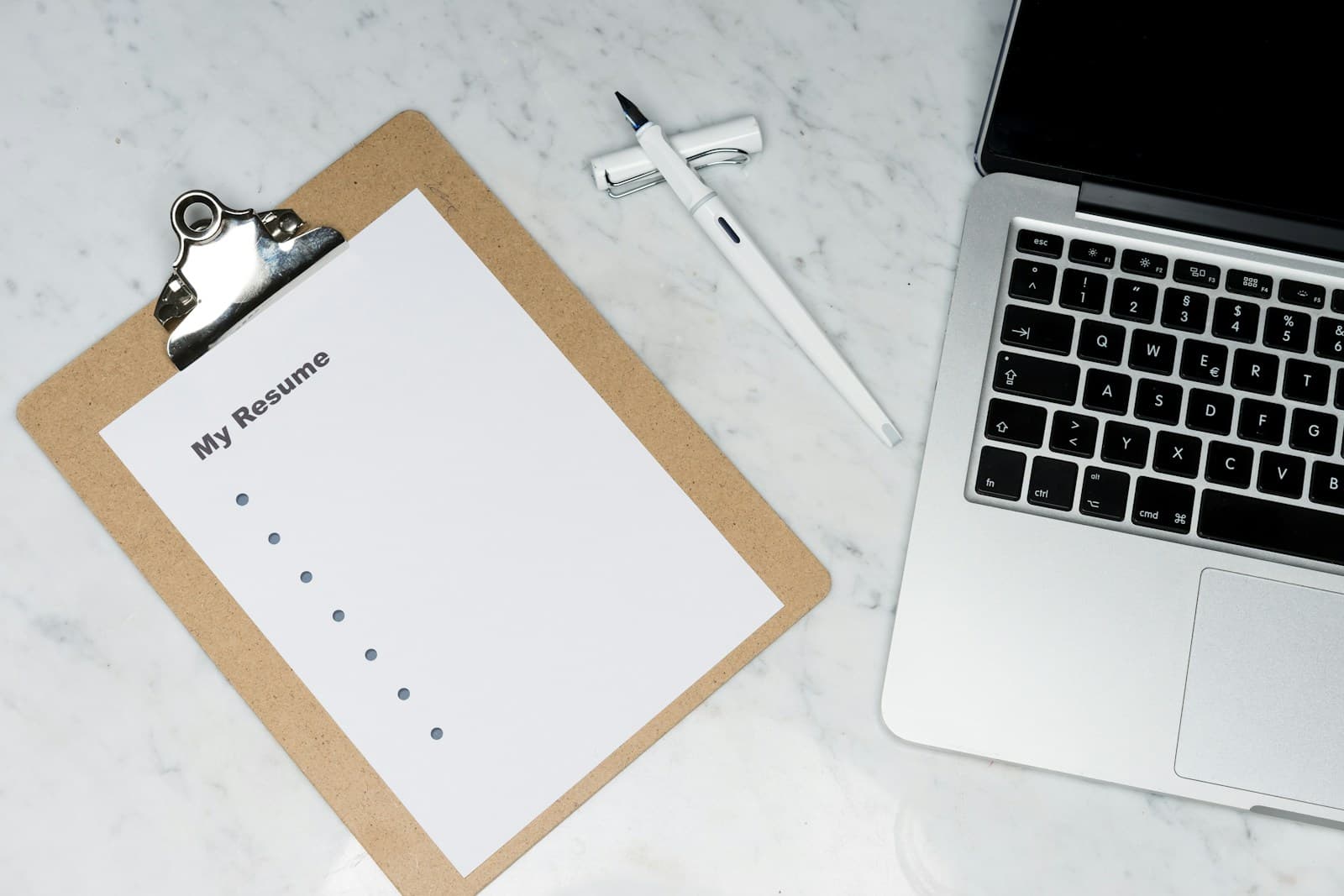 Recruteuse examinant des CV et dossiers candidats sur un bureau professionnel avec ordinateur portable.