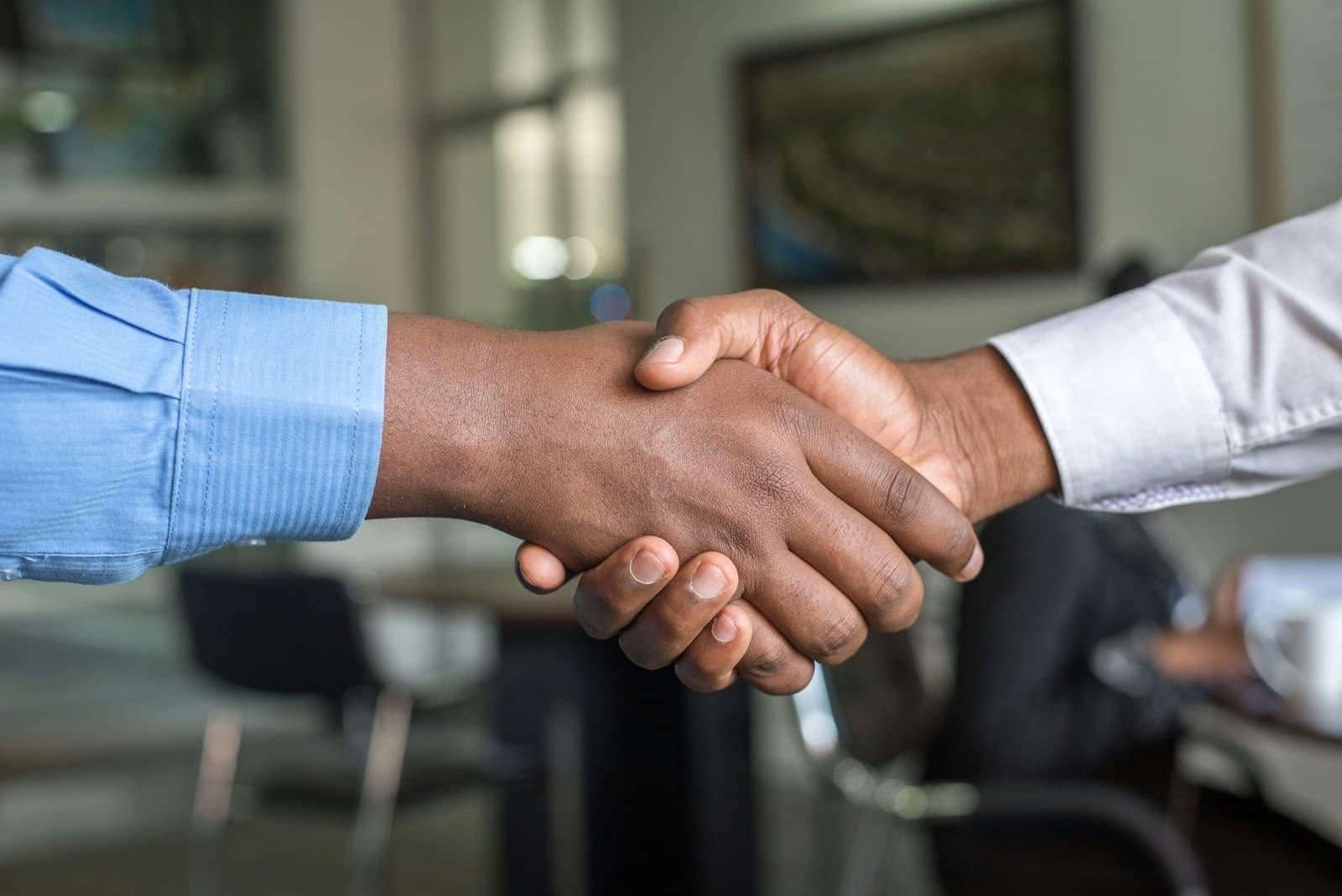 Deux professionnels se serrant la main dans un bureau, symbolisant l’accord et la décision d’embauche.