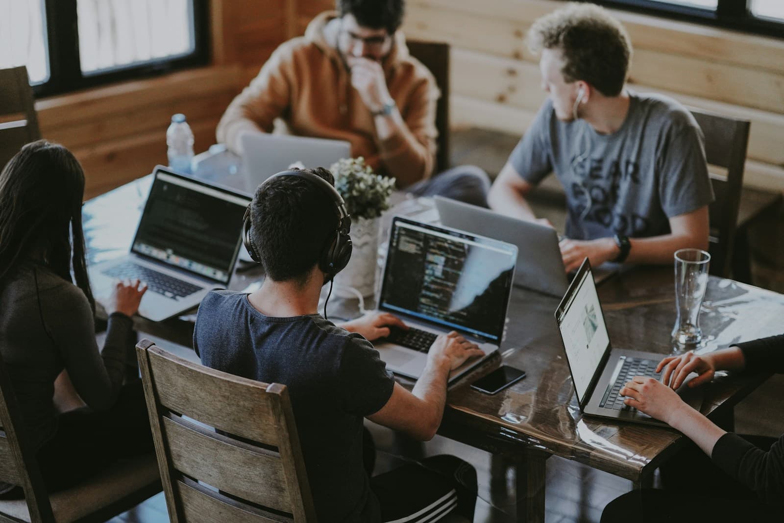 Plusieurs collaborateurs en réunion autour d'une table de bureau avec ordinateurs portables, pour aligner critères et priorités de recrutement.
